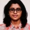 Woman with glasses and shoulder-length hair wearing a floral top, facing the camera.
