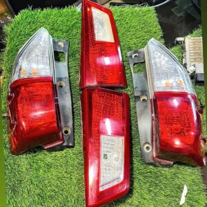 Four red and clear car tail lights placed on green artificial grass for display