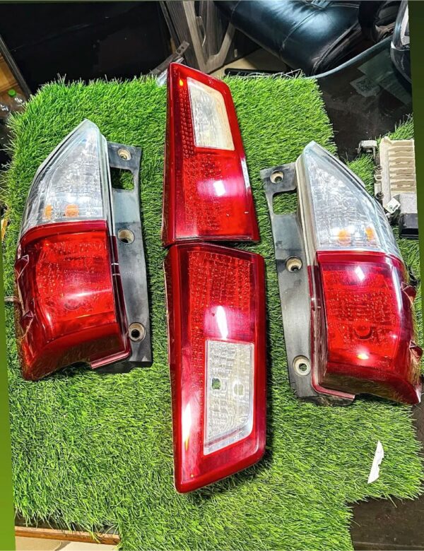 Four red and clear car tail lights placed on green artificial grass for display